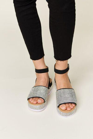 a woman wearing a pair of black and white sandals