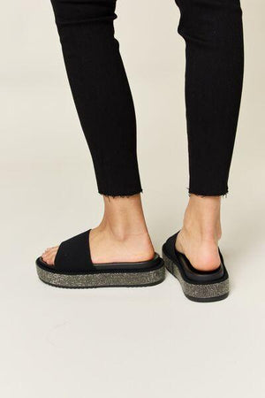 a person wearing black sandals and black pants