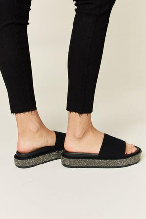 a person wearing black sandals and black pants