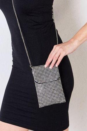 a woman in a black dress holding a silver purse