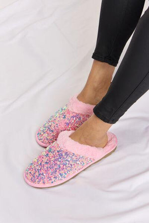 a person wearing pink slippers with colorful sprinkles