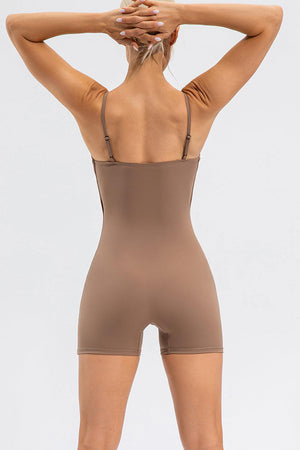 a woman in a tan bodysuit with her back to the camera
