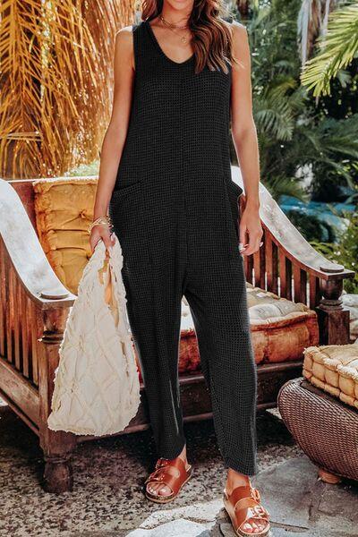 a woman in a black jumpsuit holding a white bag