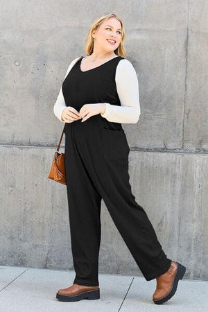 a woman in a black jumpsuit is walking down the street