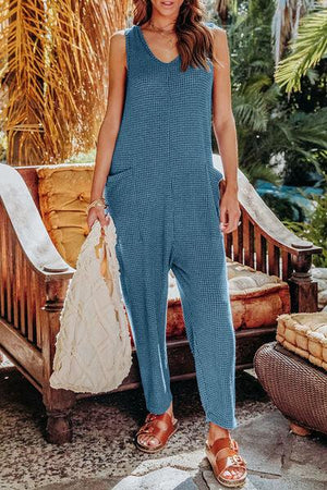 a woman in a blue jumpsuit holding a white bag