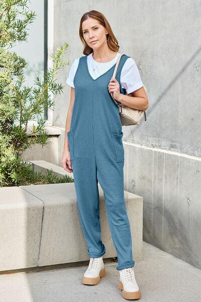 a woman in a blue jumpsuit standing next to a building