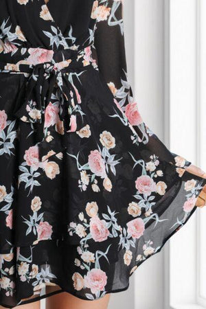 a woman wearing a black floral print dress