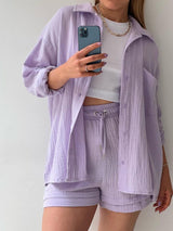 a woman in a white shirt and purple shorts holding a cell phone