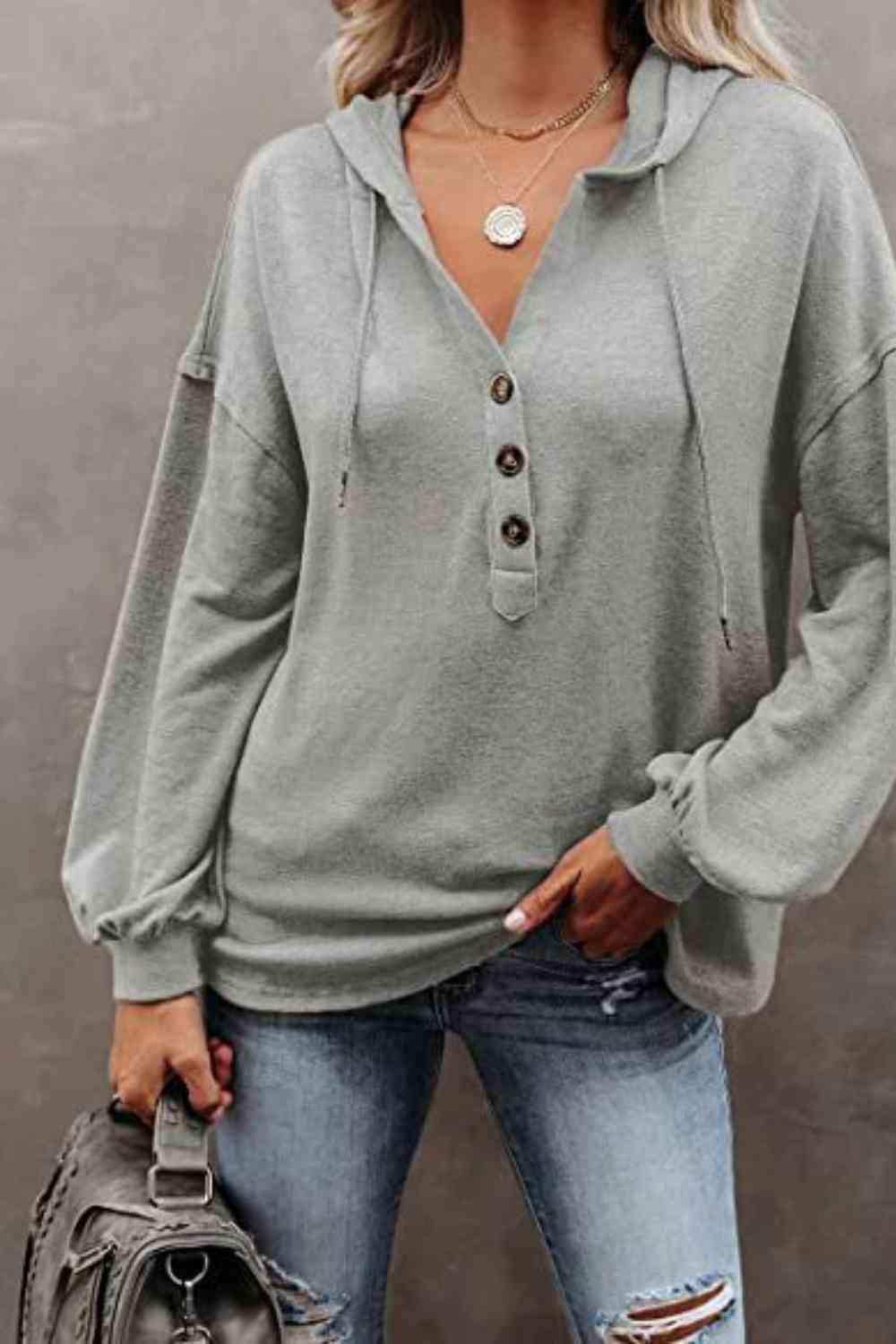 a woman wearing a grey sweater and ripped jeans