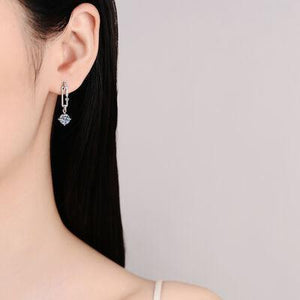 a woman wearing a pair of silver earrings