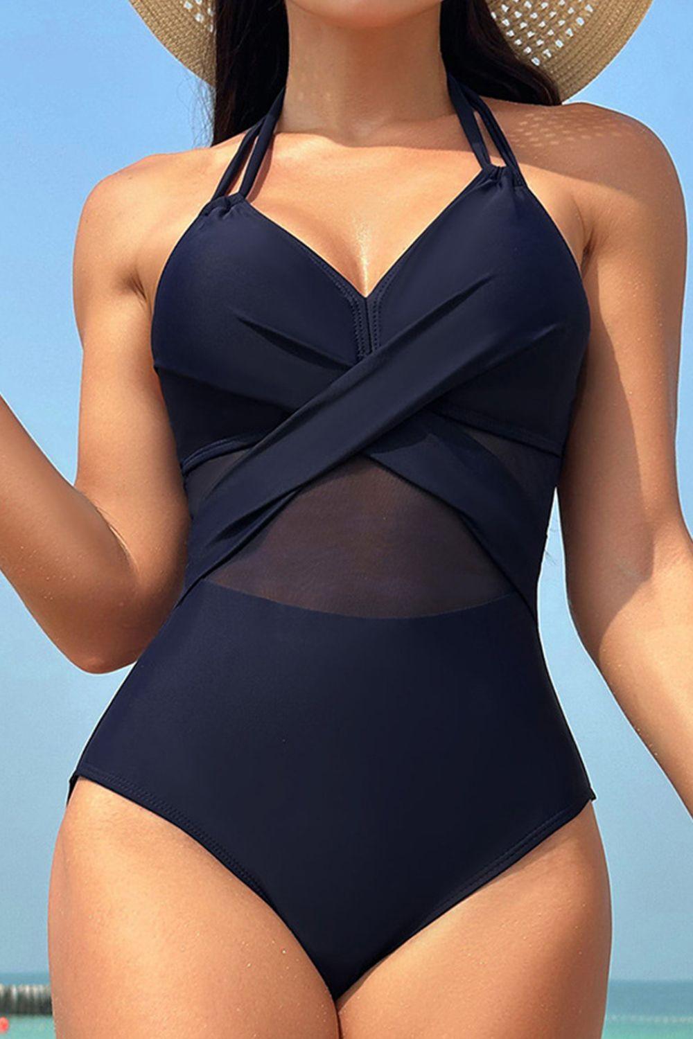 a woman in a blue one piece swimsuit on the beach
