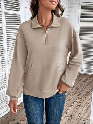 a woman wearing a tan sweatshirt and jeans