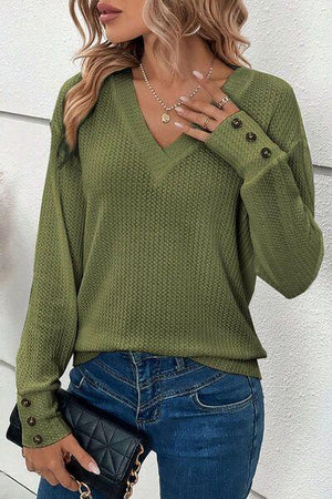 a woman wearing a green sweater and jeans