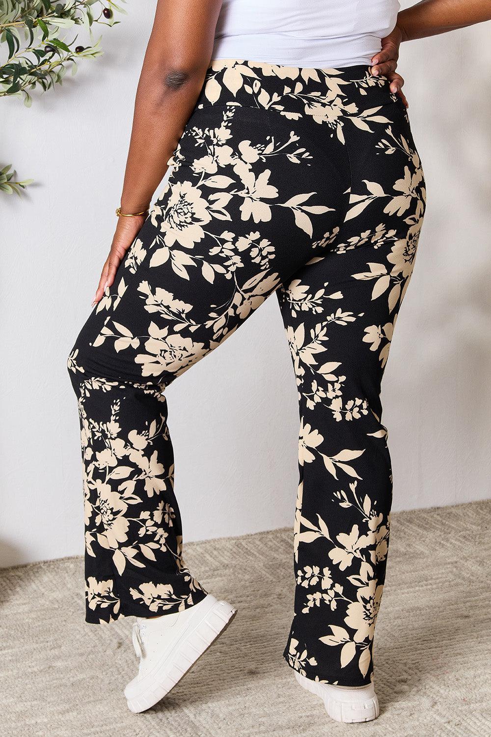 a woman in a white tank top and black floral pants