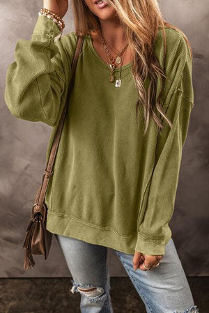 a woman wearing a green sweater and ripped jeans