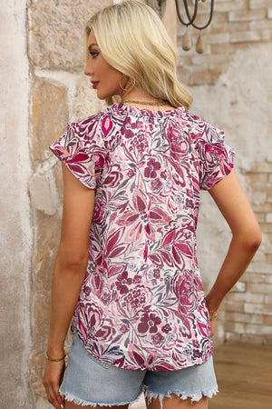 a woman wearing a short sleeve top with a floral print