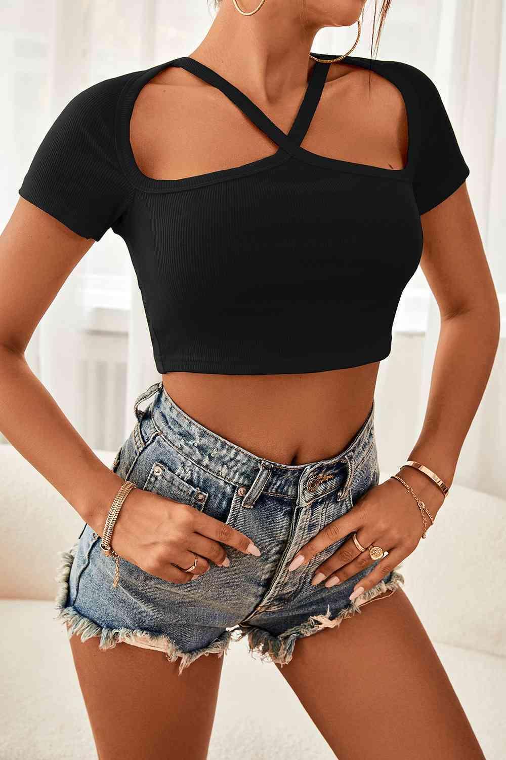a woman wearing a black crop top and denim shorts
