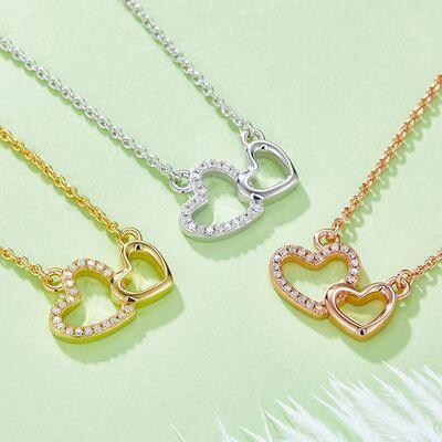 three heart necklaces on a green surface