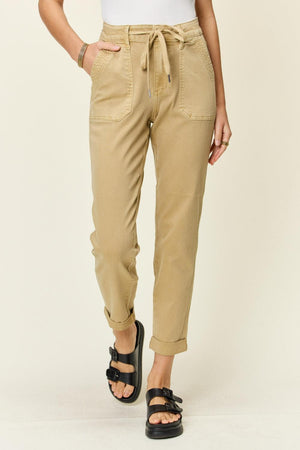 a woman wearing a white tank top and khaki pants