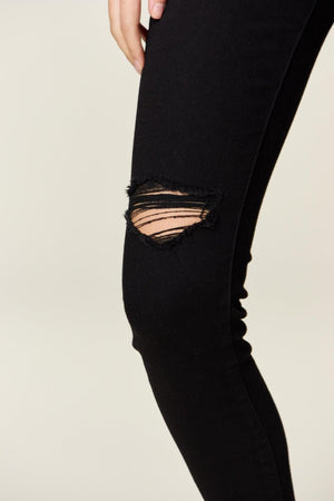 a woman in black jeans with ripped knees