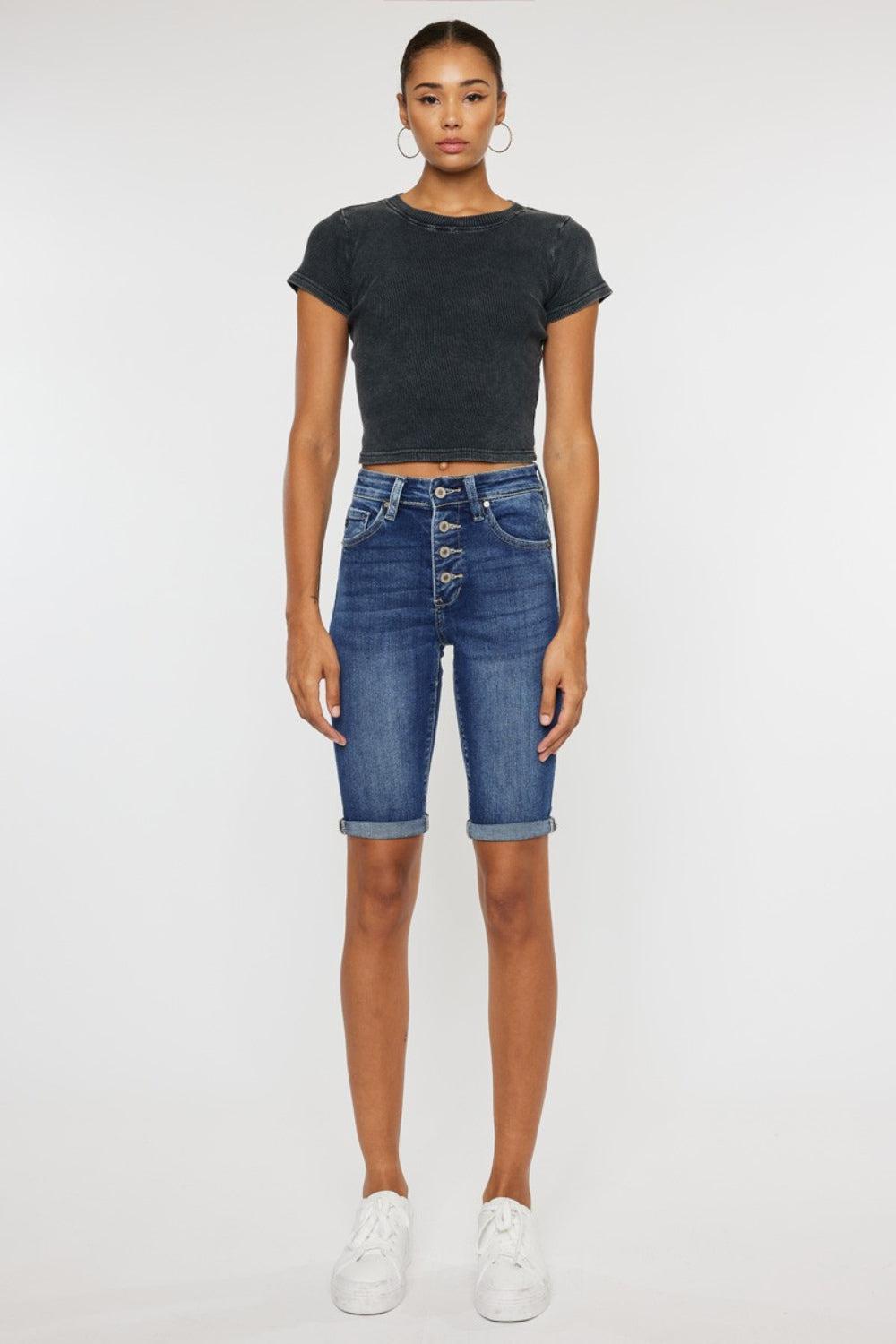 a woman wearing a black crop top and denim shorts