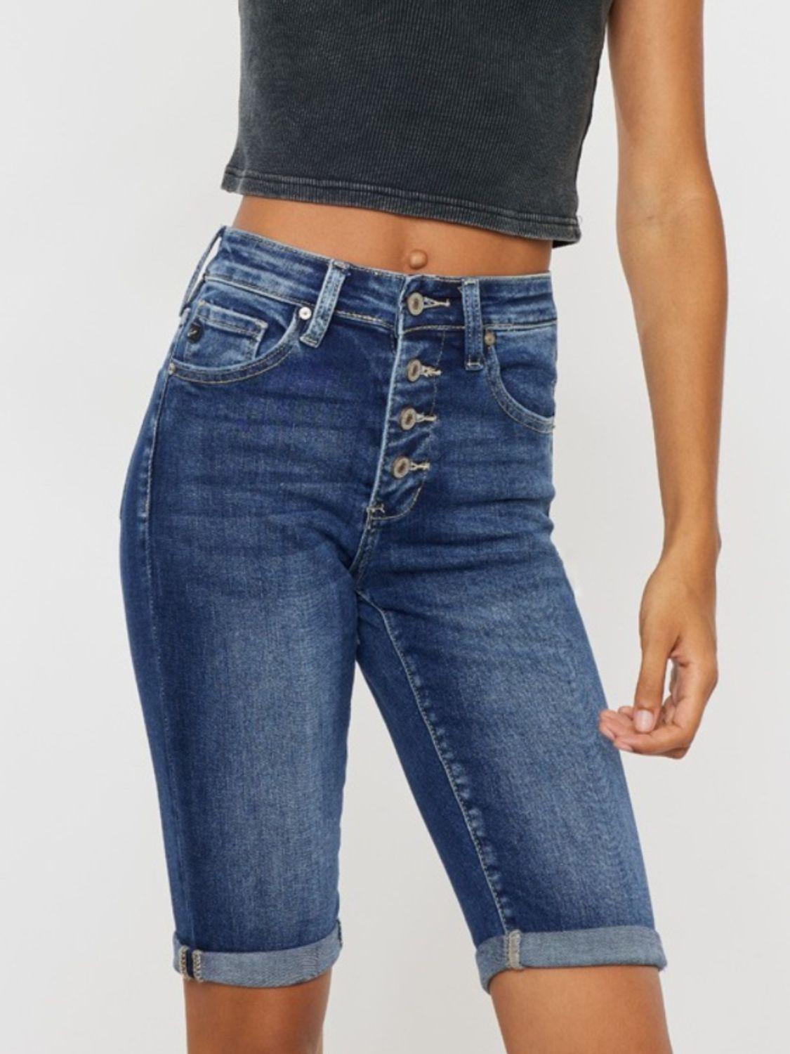 a woman wearing a black crop top and denim shorts