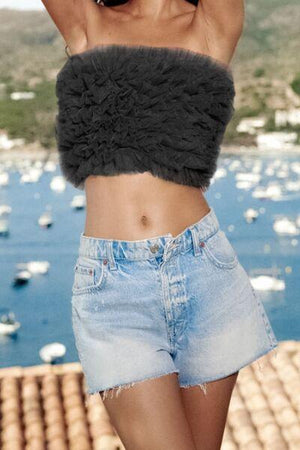 a woman wearing a crop top and denim shorts