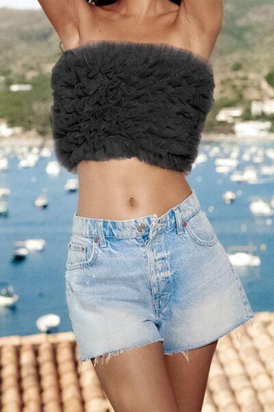a woman wearing a crop top and denim shorts