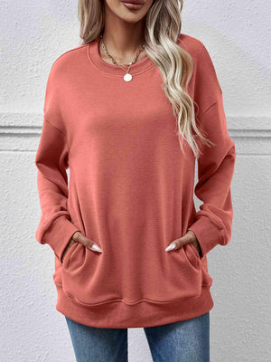 a woman wearing an orange sweatshirt and jeans