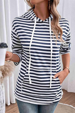 a woman wearing a striped hoodie and jeans