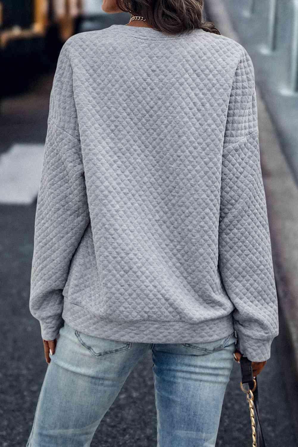 a woman wearing a grey sweater and jeans