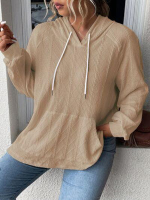 a woman wearing a tan sweater and jeans