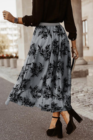 a woman wearing a black shirt and a gray floral print skirt