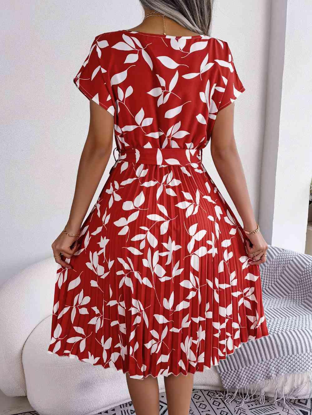 a woman wearing a red dress with white leaves on it