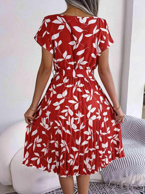 a woman wearing a red dress with white leaves on it