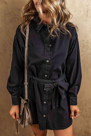 a woman in a black shirt dress with a handbag