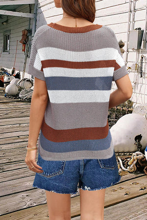 a woman standing on a wooden deck wearing a striped sweater