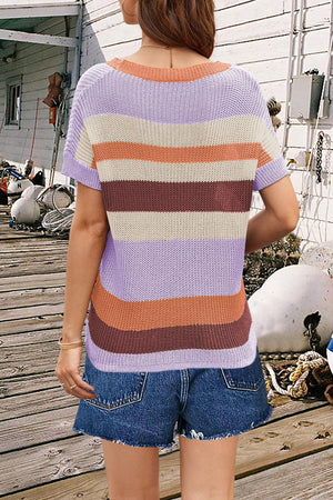 a woman standing on a wooden deck wearing a striped sweater