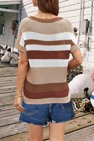 a woman standing on a wooden deck wearing a brown and white striped sweater