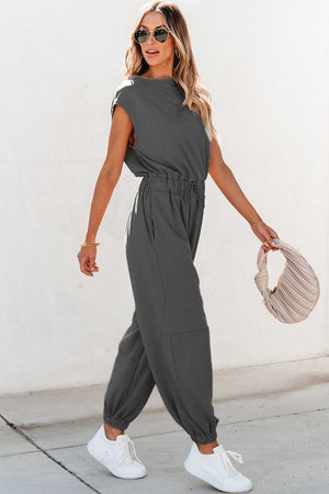 a woman in a gray jumpsuit walking down the street