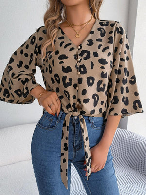 a woman wearing a leopard print shirt and jeans