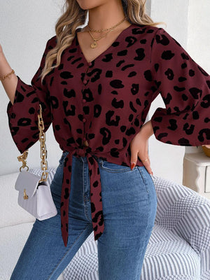 a woman wearing a leopard print blouse and jeans