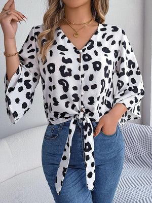 a woman wearing a leopard print shirt and jeans