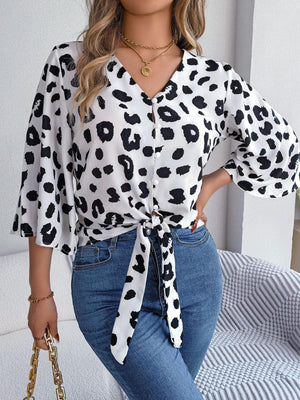 a woman wearing a leopard print shirt and jeans