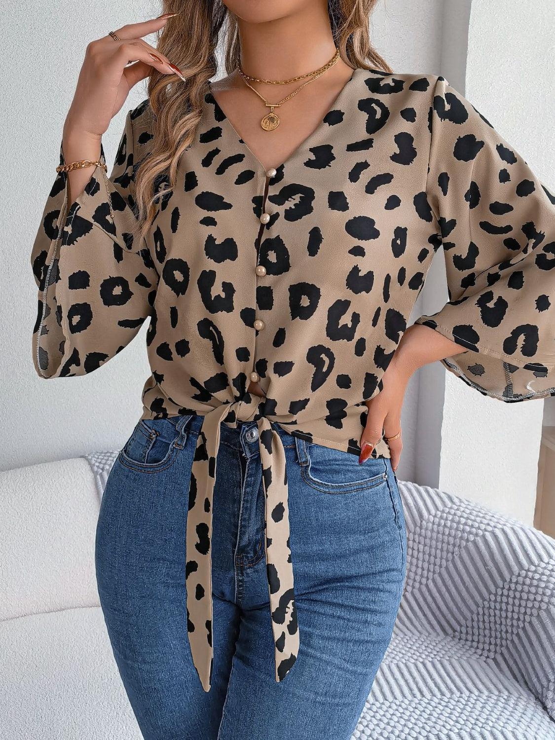a woman wearing a leopard print shirt and jeans