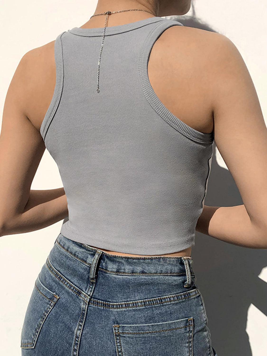 a woman wearing a gray tank top and jeans