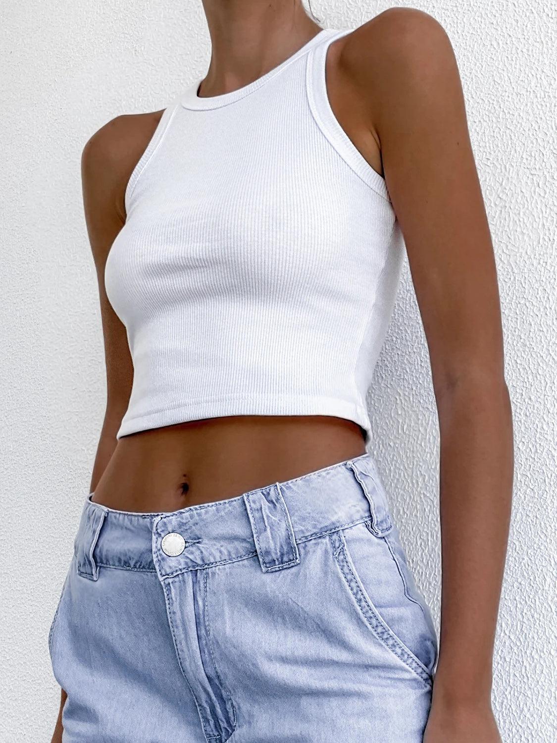 a woman wearing a white crop top and denim shorts