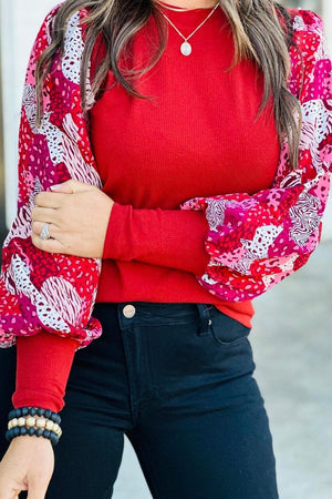 a woman wearing a red sweater and black pants