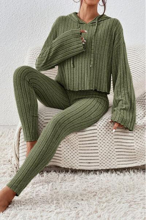 a woman sitting on a couch wearing a green sweater and pants