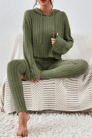 a woman sitting on a couch wearing a green sweater and pants